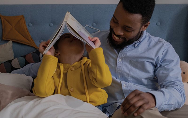 Father reading his autistic child a story in bed.